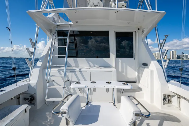 Slide: The Image of 1998 Viking 50 Convertible yacht deck with fishing setup, ocean view, and city skyline. - 24