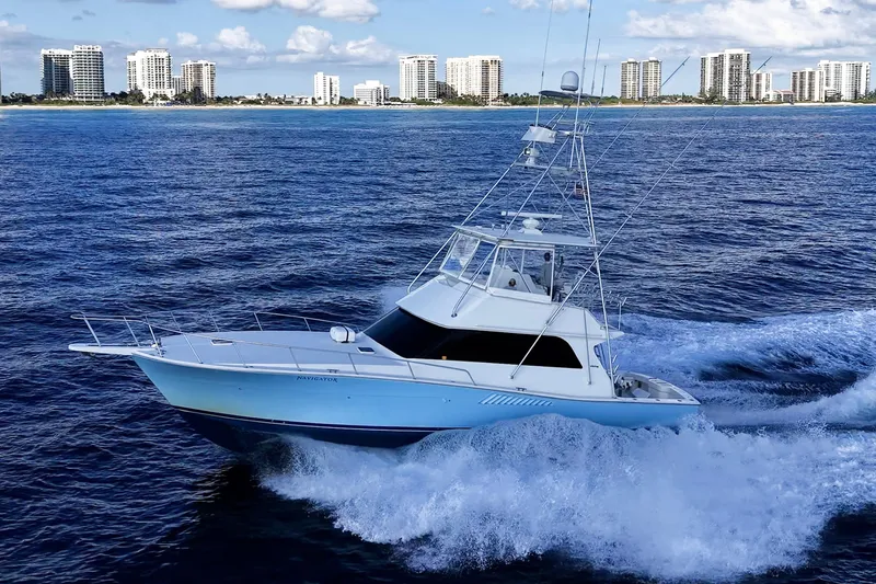Slide: The Image of 1998 Viking 50 Convertible yacht cruising on ocean with city skyline in background. - 3
