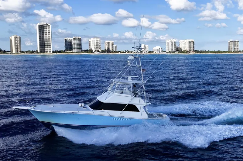 Slide: The Image of 1998 Viking 50 Convertible yacht cruising near city skyline on a sunny day. - 4