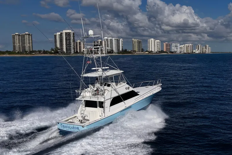 Slide: The Image of 1998 Viking 50 Convertible yacht cruising near coastal city skyline. - 6