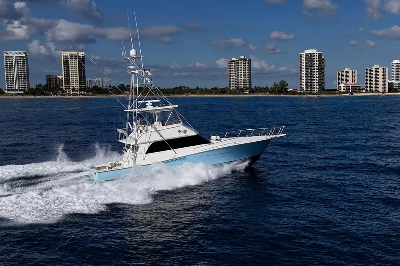 Slide: The Image of 1998 Viking 50 Convertible yacht cruising near coastal city skyline. - 7