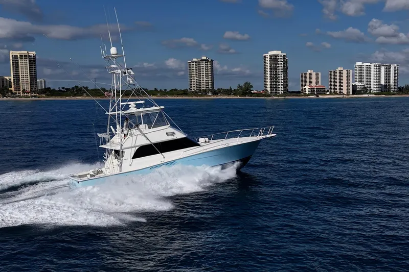 Slide: The Image of 1998 Viking 50 Convertible yacht cruising near coastal city skyline. - 8