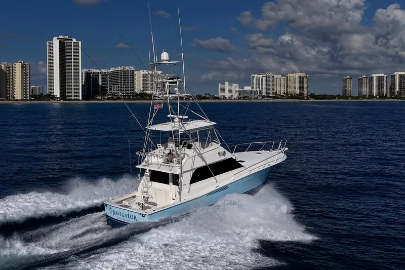 Slide: The Image of 1998 Viking 50 Convertible yacht cruising near city skyline on a sunny day. - 9