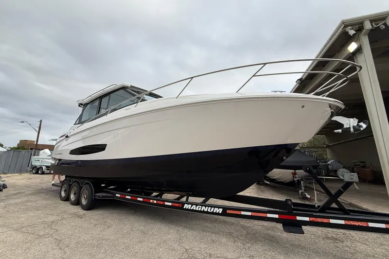 Slide: The Image of 2026 Regal 36 Grande Coupe boat on trailer, parked outdoors under cloudy sky. - 1
