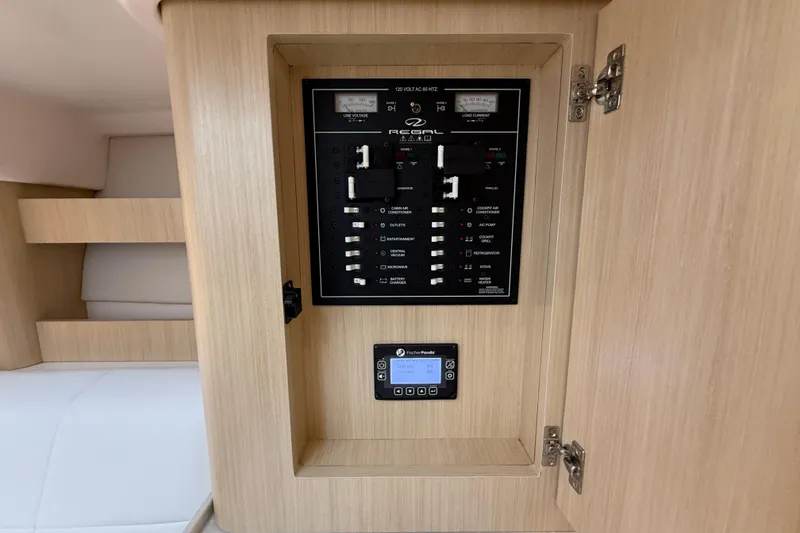 Slide: The Image of Electrical panel inside 2026 Regal 36 Grande Coupe yacht, featuring modern controls and wood finish. - 107