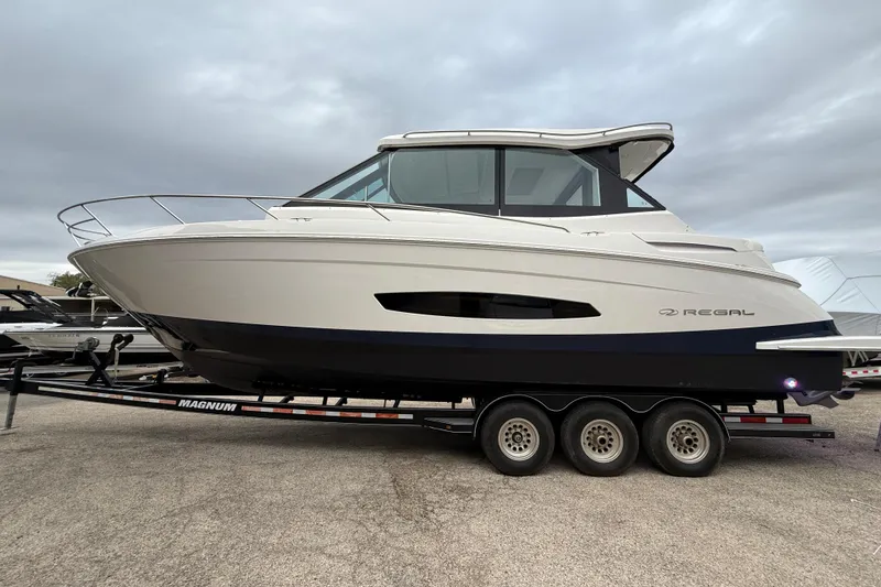 Slide: The Image of 2026 Regal 36 Grande Coupe boat on trailer under cloudy sky. - 4