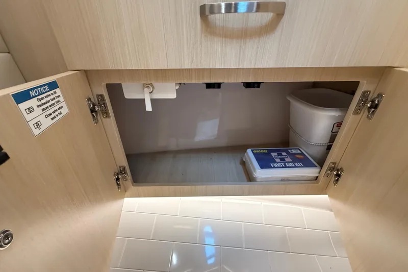 Slide: The Image of Open cabinet in 2026 Regal 36 Grande Coupe with first aid kit and bucket inside. - 91