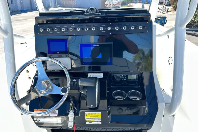 Slide: The Image of 2023 Wellcraft 222 Scarab Offshore boat dashboard with steering wheel and control panel. - 11