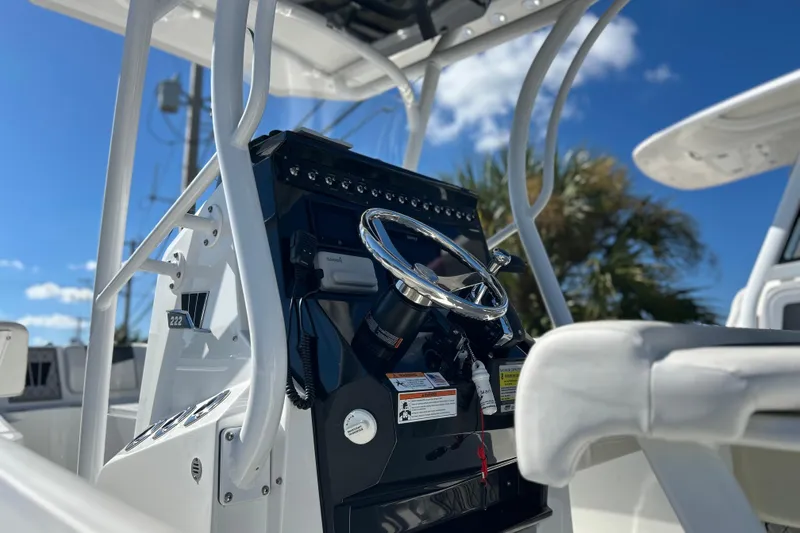 Slide: The Image of 2023 Wellcraft 222 Scarab Offshore boat console with steering wheel under blue sky. - 8