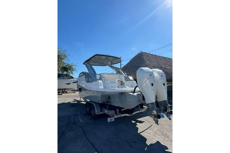 Slide: The Image of 2024 NX Boats NX290 with dual outboard motors on a trailer under clear blue sky. - 3