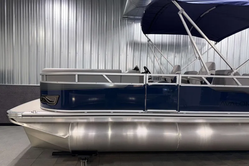 Slide: The Image of 2026 Avalon Venture 2385 QL pontoon boat with blue exterior and canopy in showroom. - 5