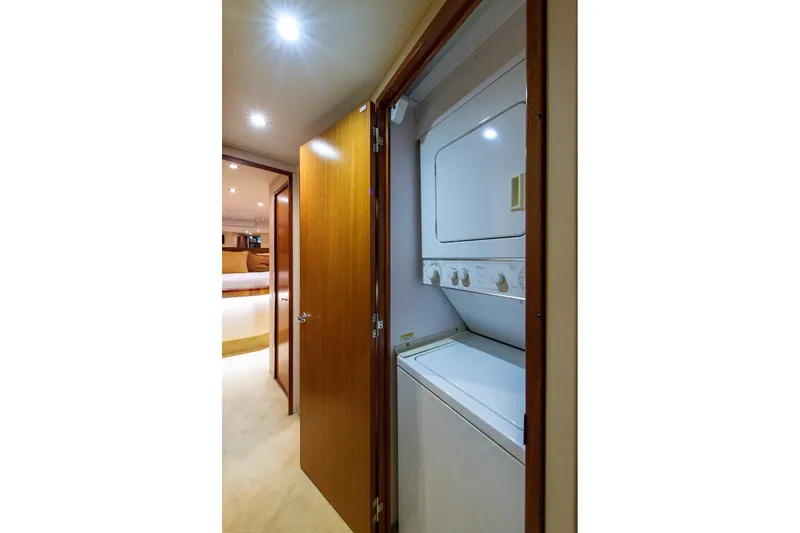 Slide: The Image of Laundry area inside 2006 Hatteras 64 Convertible yacht, featuring a stacked washer and dryer. - 18