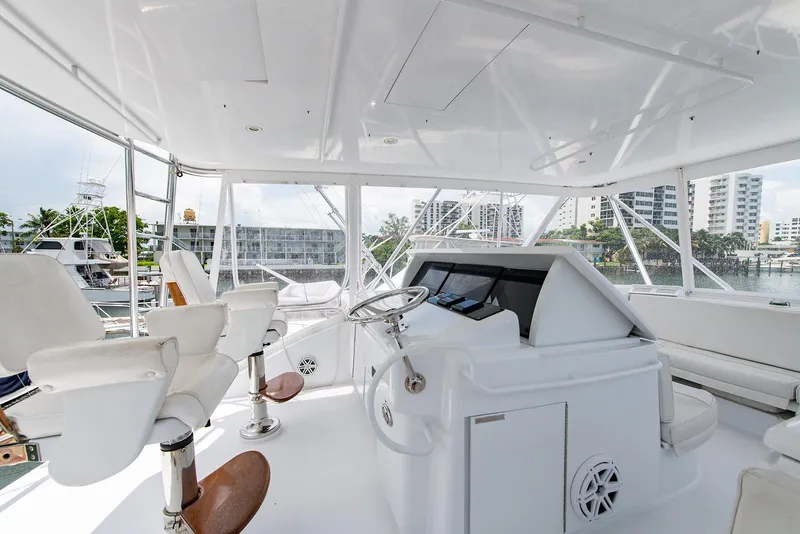 Slide: The Image of 2006 Hatteras 64 Convertible yacht helm with white seating and marina view. - 19