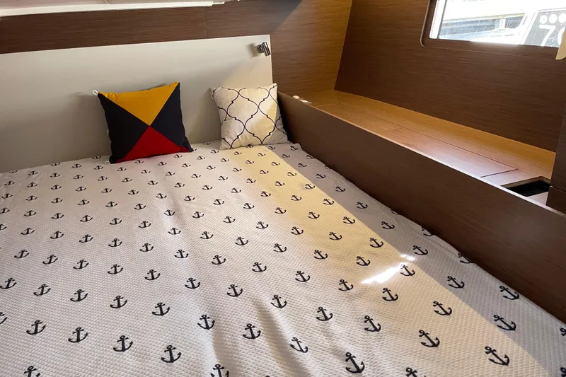 Slide: The Image of Cozy cabin interior of 2024 Beneteau Oceanis 51.1 with nautical-themed bedding and pillows. - 10