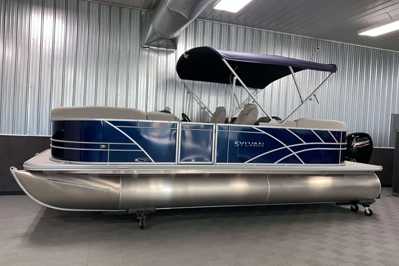 Slide: The Image of 2026 Sylvan Mirage 8522 LZ pontoon boat with blue exterior in a showroom. - 14