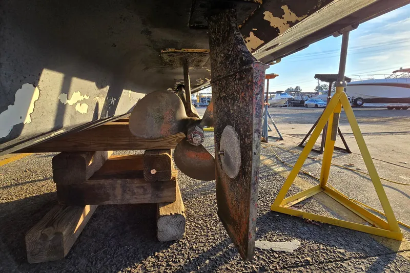 Slide: The Image of Underneath view of a 2001 Sea Ray 310 Sundancer boat on dry dock, showing propeller and rudder. - 10