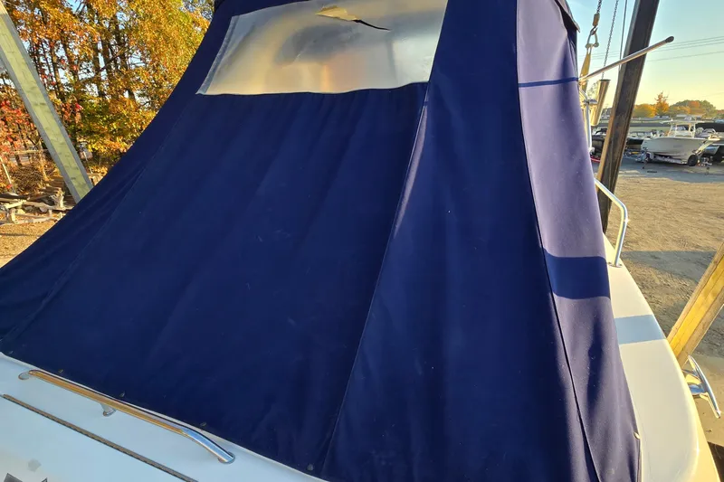 Slide: The Image of 2001 Sea Ray 310 Sundancer with blue canvas cover in a marina setting. - 12