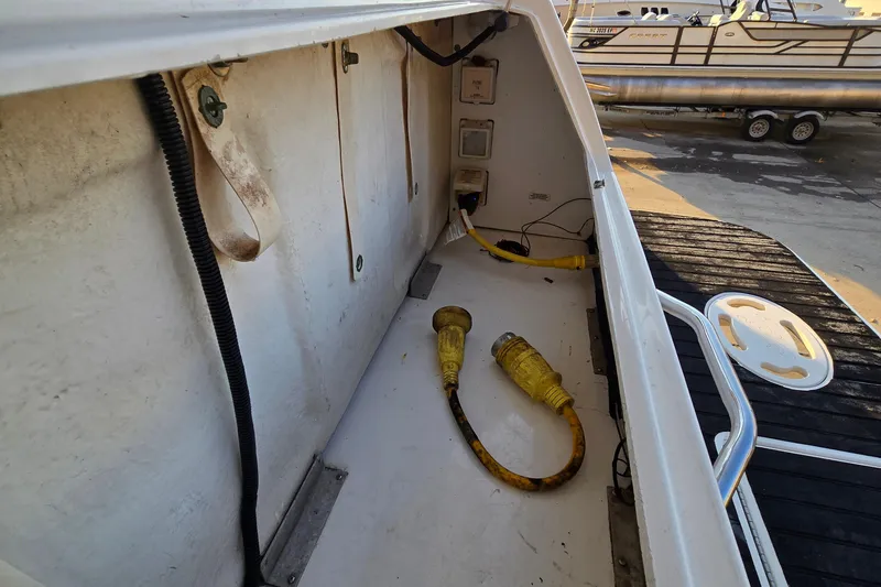 Slide: The Image of 2001 Sea Ray 310 Sundancer boat compartment with yellow power cables and dock view. - 15
