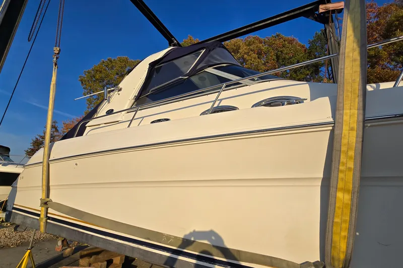 Slide: The Image of 2001 Sea Ray 310 Sundancer boat on lift, side view, under clear blue sky. - 4