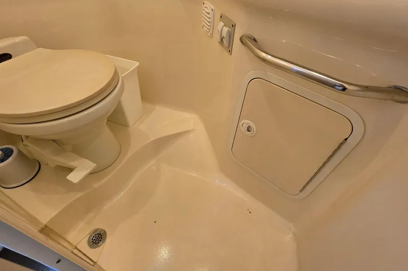 Slide: The Image of 2001 Sea Ray 310 Sundancer bathroom with toilet, storage compartment, and handrail. - 73