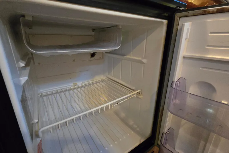 Slide: The Image of Empty refrigerator inside a 2001 Sea Ray 310 Sundancer boat. - 83