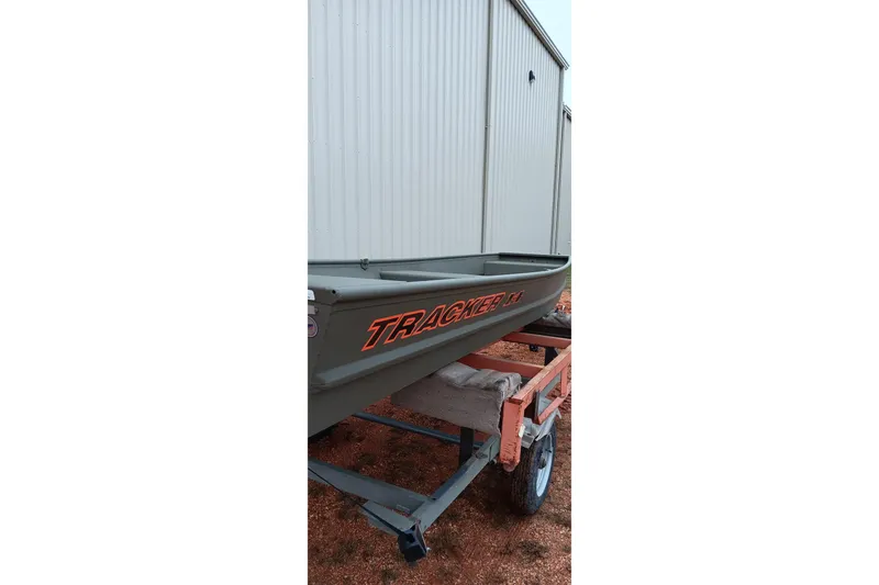 Slide: The Image of 2026 Tracker Grizzly 1436 Jon boat on trailer near metal building. - 13
