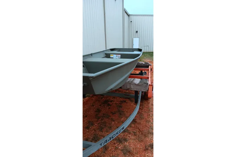 Slide: The Image of 2026 Tracker Grizzly 1436 Jon boat on trailer near industrial building. - 5