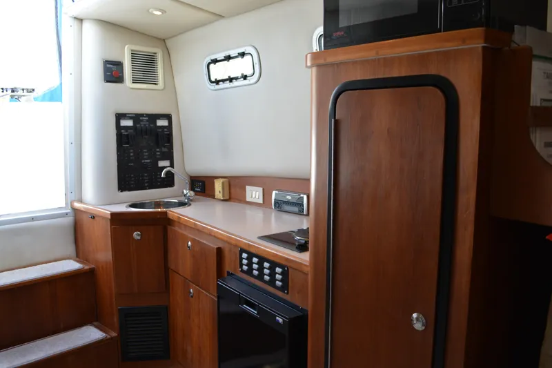 Slide: The Image of 2001 Shamrock 290 Walkaround cabin interior with wood cabinetry and compact kitchen area. - 20
