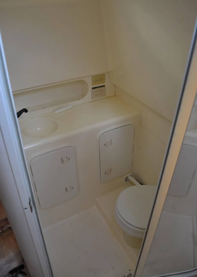 Slide: The Image of 2001 Shamrock 290 Walkaround boat bathroom with sink, toilet, and storage cabinets. - 22