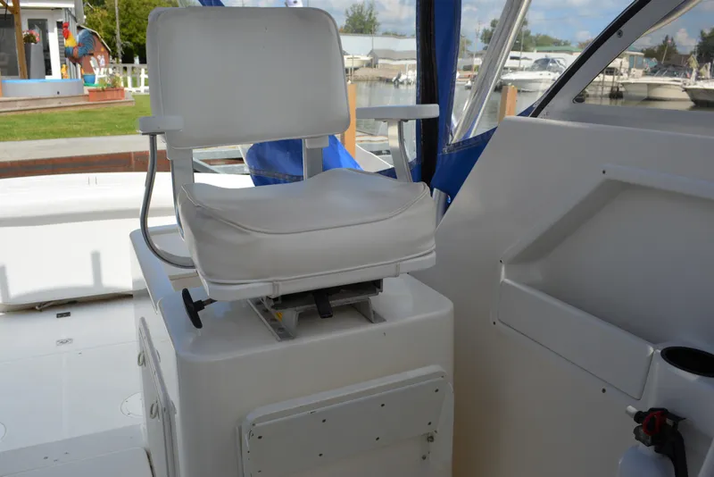 Slide: The Image of Captain's chair on 2001 Shamrock 290 Walkaround boat, featuring white upholstery and blue accents. - 24