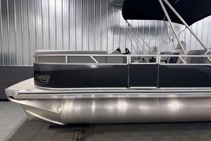 Slide: The Image of 2026 Avalon Venture 2385 QL Tritoon boat in a showroom with sleek design and canopy. - 5