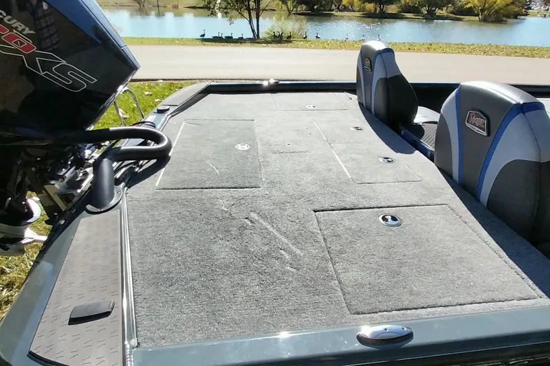 Slide: The Image of 2025 Ranger ALPHA 208 boat interior with carpeted deck and seating by a lake. - 3