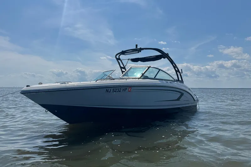 The Image of 2021 Chaparral 23 SSi boat on calm water under a clear blue sky. - 1