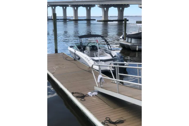 Slide: The Image of 2021 Chaparral 23 SSi boat docked by a wooden pier under a bridge. - 6