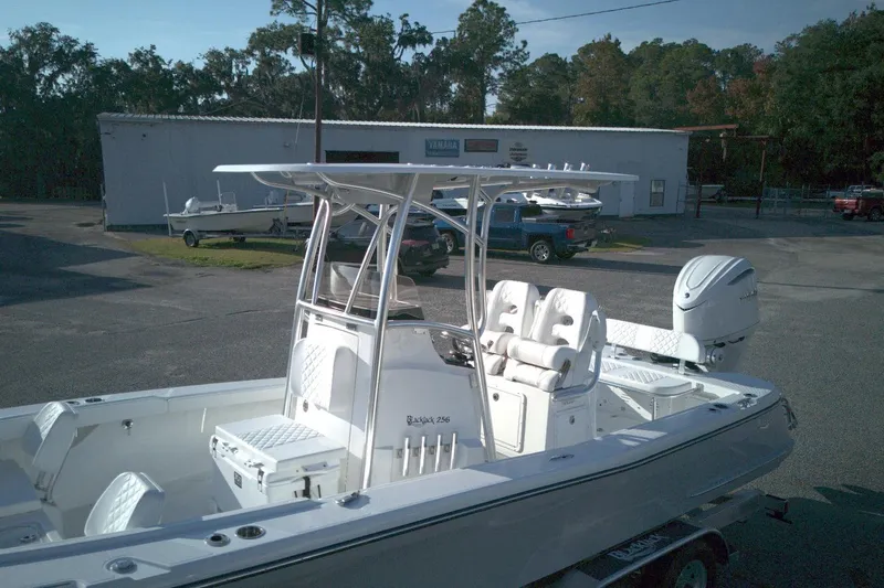 Slide: The Image of 2026 BlackJack 256 Coastal boat with T-top and outboard motor in a parking lot. - 4
