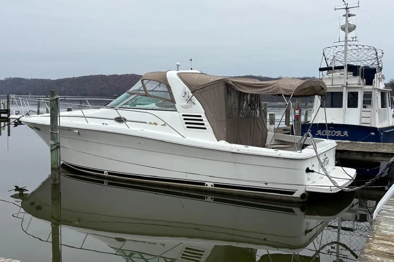 The Image of 1997 Sea Ray 330 Express Cruiser docked at a marina, calm water reflection. - 0
