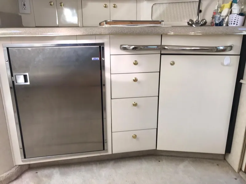 Slide: The Image of 1997 Sea Ray 330 Express Cruiser kitchen with stainless steel fridge and white cabinetry. - 12