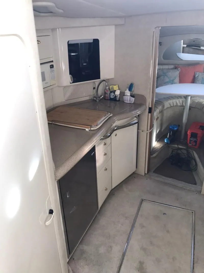 Slide: The Image of 1997 Sea Ray 330 Express Cruiser interior with kitchenette and cozy sleeping area. - 18