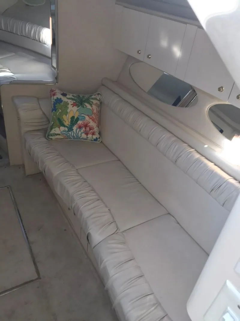 Slide: The Image of 1997 Sea Ray 330 Express Cruiser interior with beige seating and colorful pillow. - 19
