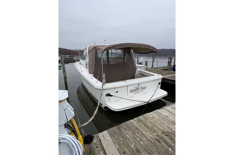 Slide: The Image of 1997 Sea Ray 330 Express Cruiser docked, featuring a covered deck and calm waters. - 2