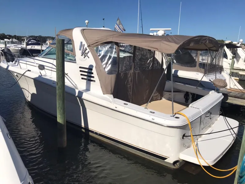 Slide: The Image of 1997 Sea Ray 330 Express Cruiser docked at marina, featuring tan canopy and sleek design. - 3