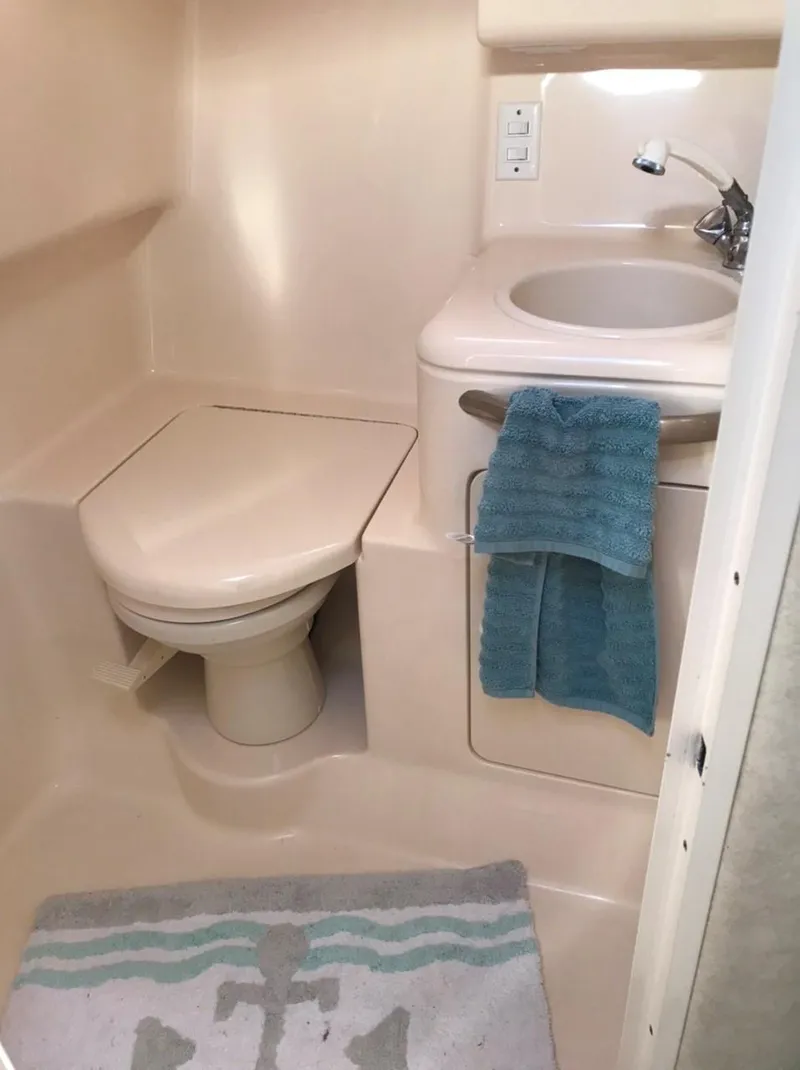 Slide: The Image of 1997 Sea Ray 330 Express Cruiser bathroom with toilet, sink, and blue towels. - 9