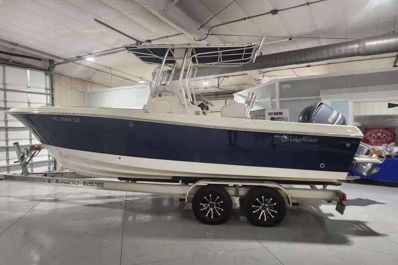 Slide: The Image of 2012 Edgewater 228CC boat in showroom, blue and white hull, indoor display. - 0
