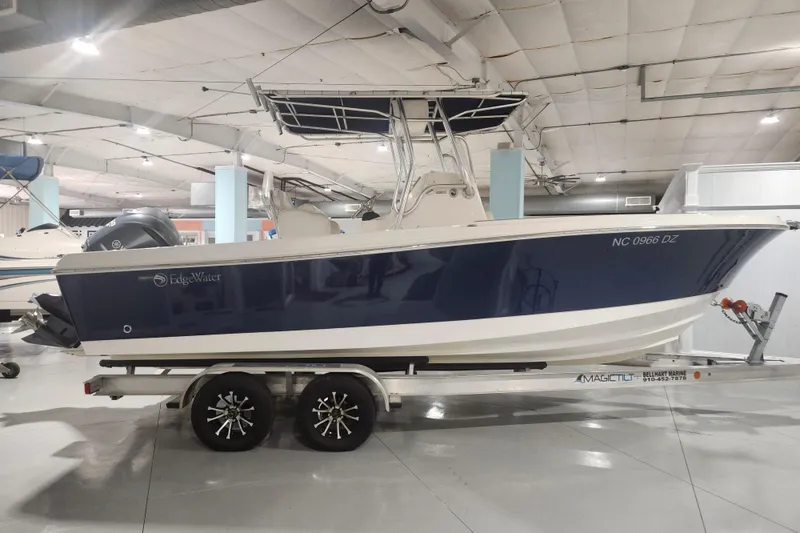 Slide: The Image of 2012 Edgewater 228CC boat displayed indoors, showcasing sleek blue hull design. - 1