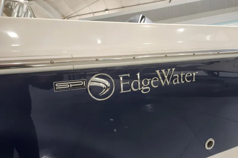 Slide: The Image of 2012 Edgewater 228CC boat displayed indoors, blue and white hull, on wheeled supports. - 2