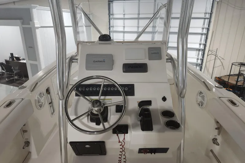 Slide: The Image of 2012 Edgewater 228CC boat interior with helm, seating, and T-top in a showroom. - 8