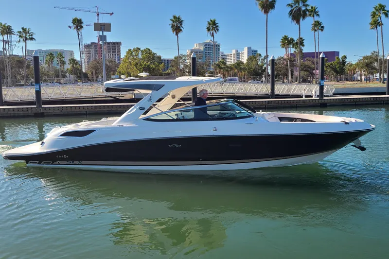 The Image of 2014 Sea Ray 350 SLX boat cruising in a marina with cityscape background. - 0