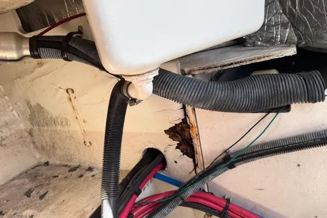 Slide: The Image of 2014 Sea Ray SLX 350 interior showing damaged area with exposed wiring and tubing. - 36