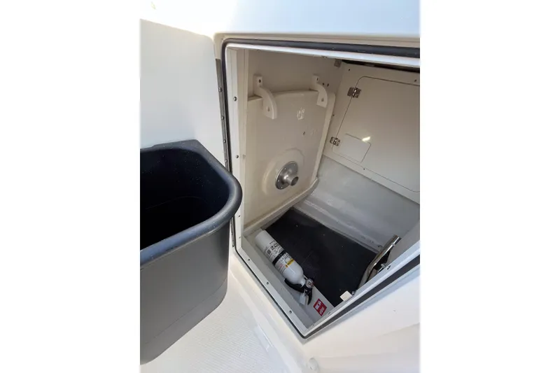 Slide: The Image of 2026 Robalo R257 Dual Console storage compartment with fire extinguisher and trash bin. - 11