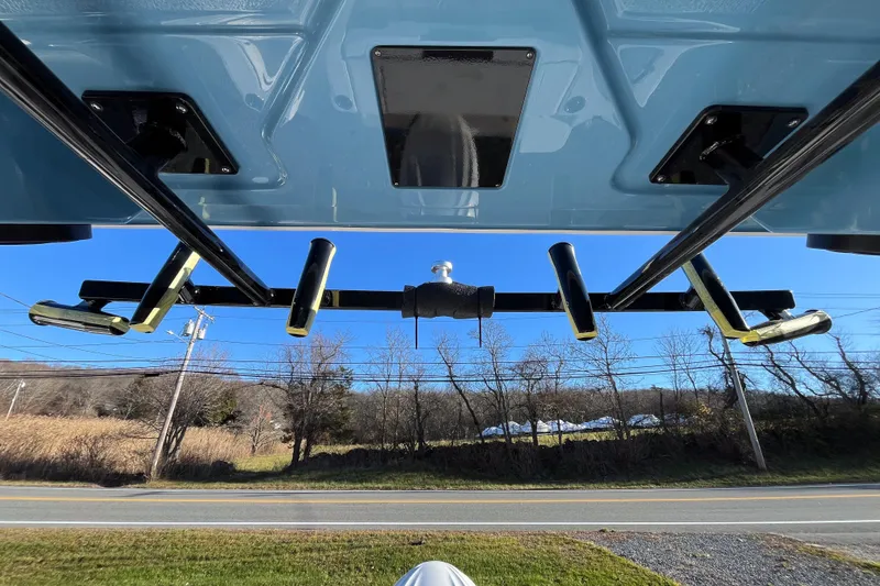 Slide: The Image of 2026 Robalo R257 Dual Console boat underside with rod holders, clear sky background. - 18